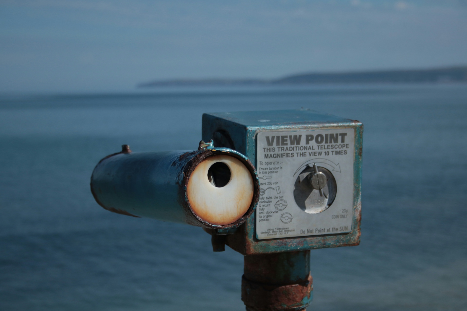 A coin operated viewpoint telescope looking out over calm sea