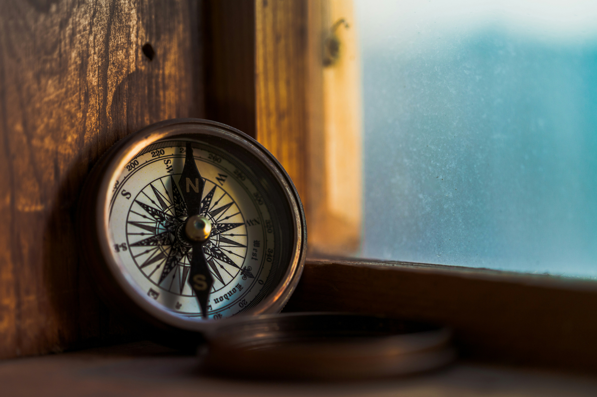 A brass compass resting on a wooden window ledge in warm light